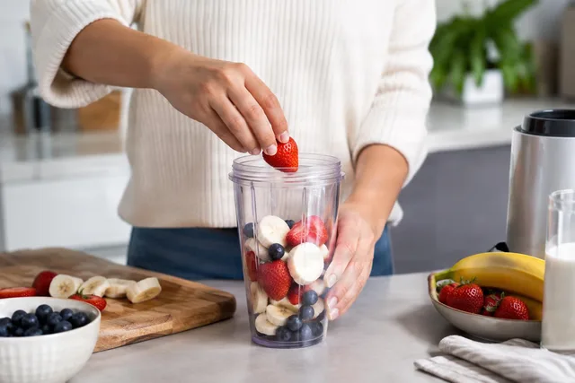 Hands Adding Fruit to Blender