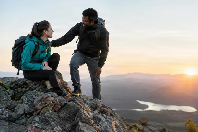 Hiker Helping Friend at Sunset