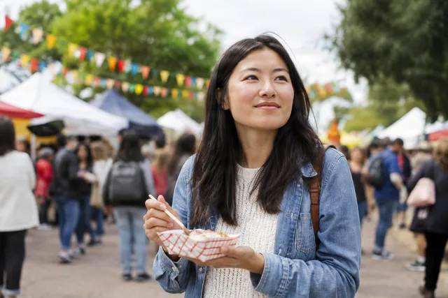 Woman Enjoying Food at Street Festival