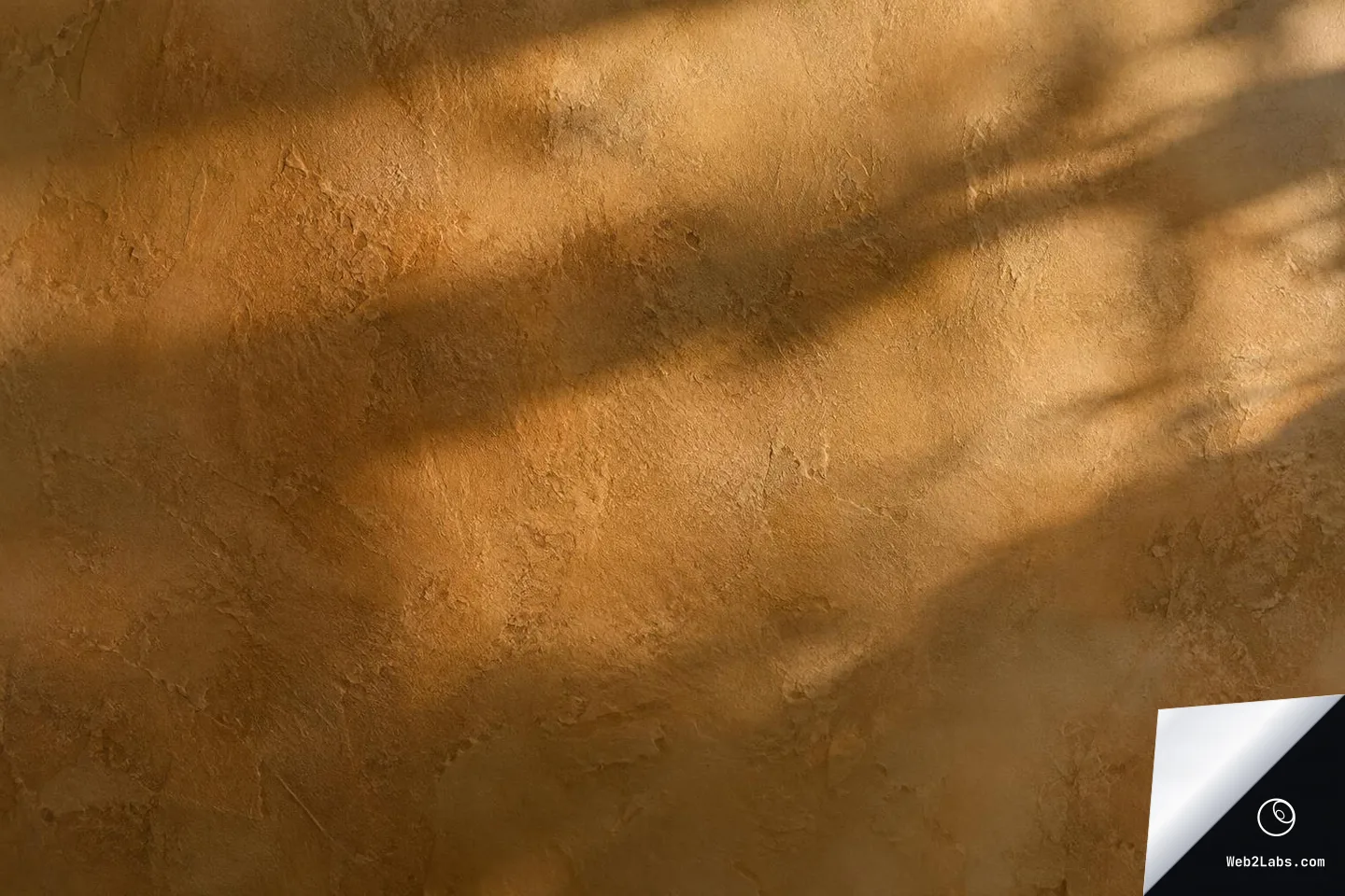 Close-up of a warm tan plaster wall with subtle texture and soft diagonal shadows across the surface.