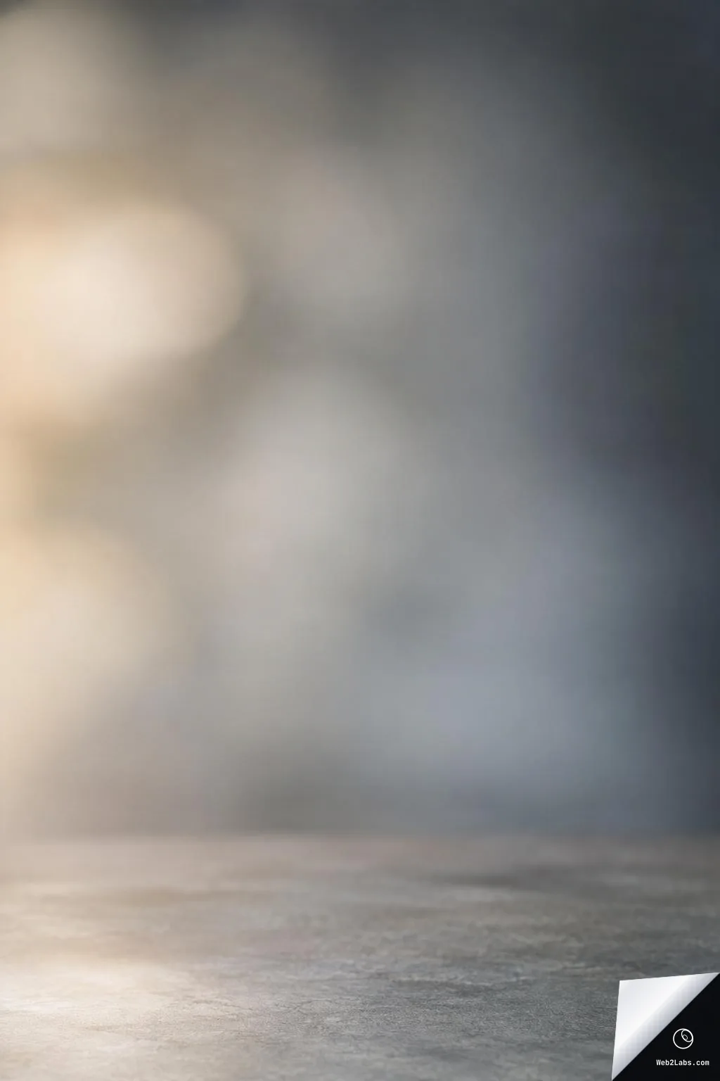 Blurred studio background with soft circular bokeh lights in beige and gray-blue tones, with a subtle textured surface along the bottom edge.